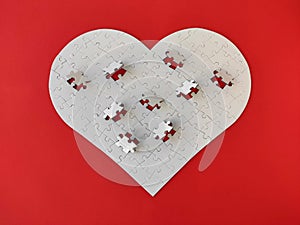 Heart shaped blank white jigsaw puzzle on red background puzzle pieces completing the heart shape