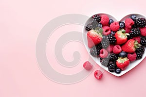 Heart shaped bowl with fresh berries on pink background, copy space.