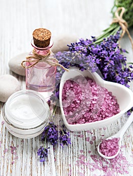 Heart-shaped bowl with sea salt, oil and fresh lavender flowers