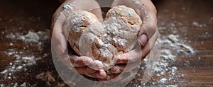 The heart-shaped bread being lovingly crafted by hands on a wooden table..AI generated image photo