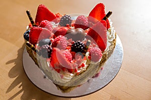 Heart shaped cake with red ripe strawberries and fresh berries, raspberries and blueberries. St. Valentine`s Day, Mother`s Day,