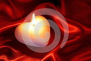 Heart shaped candle on red silk