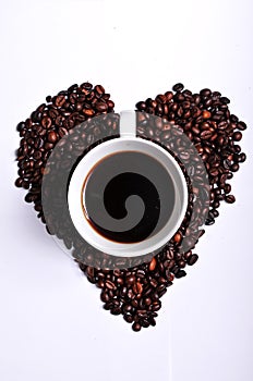 Heart shaped cofee beans with a cup of coffee in the middle