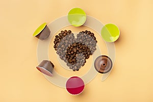 Heart shaped coffee beans and capsules around on beige background photo