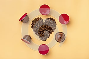 Heart shaped coffee beans and capsules around on beige background photo