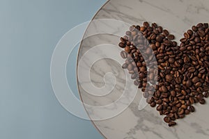 Heart shaped coffee beans, on a white marble plate. Top view