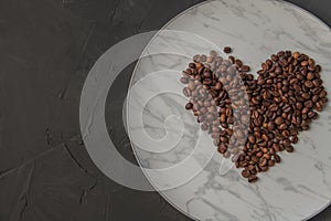 Heart shaped coffee beans, on a white marble plate. Top view