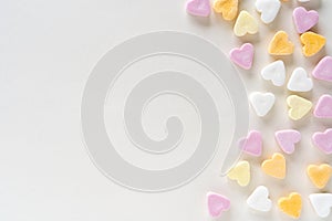 Heart shaped colourful candy on white background with copy space, sweets in pink, white, yellow, orange, pink pastels