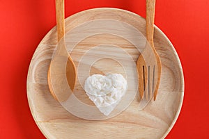 Heart shaped cooked rice in wooden plate on red background.