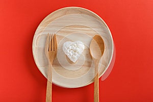 Heart shaped cooked rice in wooden plate on red background.