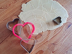 Heart shaped cookie cutter with cut hearts. Wooden rustic background, Valentine's Day, greeting card, pastry, Copy space