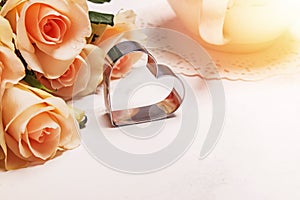 Heart shaped cookie cutter and roses on white background