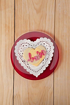 Heart shaped cookie iced with pink cream in text babe