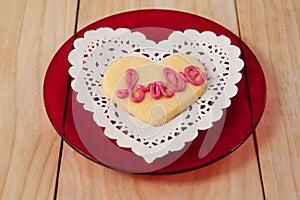 Heart shaped cookie iced with pink cream in text babe