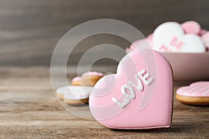 Heart shaped cookie with word Love on wooden table, closeup and space for text. Valentine`s day treat