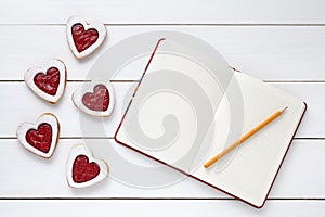 Heart shaped cookies with empty notebook frame and pencil composition for Valentines Day