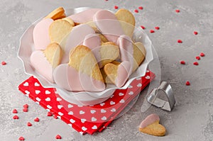 Heart-shaped cookies with pink chocolate glaze for Valentine`s Day on a white stand on the gray background.