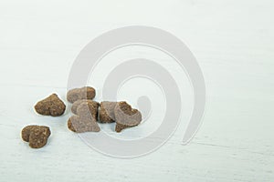 Heart shaped dog or cat kibble seen from above on a light blue w