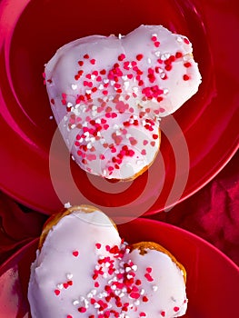 Heart-shaped donuts with tiny red heart sprinkles on red plates