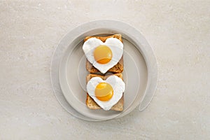 Heart shaped egg in tosted slice of rye bread on ceramic plate. Love breakfast design. Healthy sandwich. Festive lunch