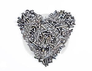A heart shaped figure laid out from various assorted rusty metal old bolts, screws, nails, nuts. The concept of metallic