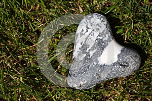 Heart shaped flintstone lying in the grass with copy space photo