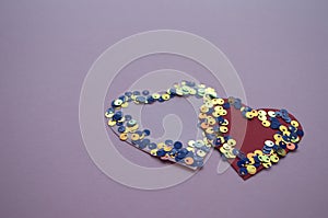 Heart shaped frame made of shiny sequins on a blue background. Festive texture for Valentines Day, Mothers Day, Womens