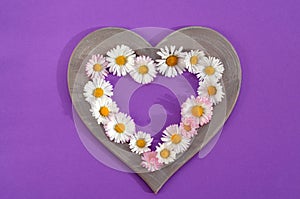 heart shaped frame with whole flowers on a purple background