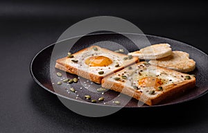 Heart shaped fried egg in bread toast with sesame seeds, flax seeds and pumpkin seeds on a black plate