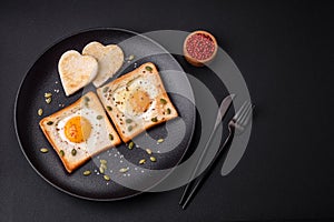 Heart shaped fried egg in bread toast with sesame seeds, flax seeds and pumpkin seeds on a black plate