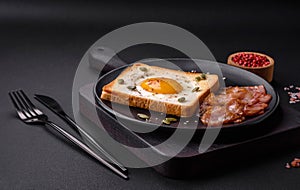 Heart shaped fried egg in bread toast with sesame seeds, flax seeds and pumpkin seeds on a black plate