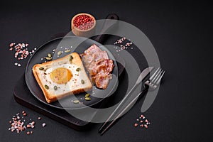 Heart shaped fried egg in bread toast with sesame seeds, flax seeds and pumpkin seeds on a black plate