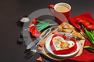 Heart-shaped fried egg served with toasted bread. Romantic art food idea for Valentine\'s breakfast