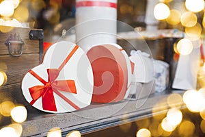 Heart-shaped gift box with a red bow on the shop window with gold bokeh