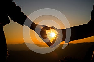 Heart shaped hands on hill at the sunset time