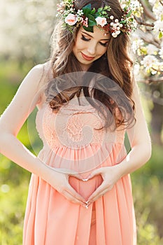 Heart shaped hands of pregnant woman on her belly