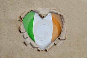 Heart shaped hole torn through paper, showing Irish flag