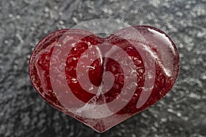 heart shaped ice cube with raspberries trapped inside, macro shot