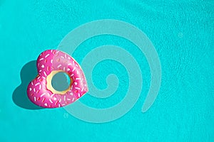 Heart shaped inflatable ring floating in swimming pool, top view with space for text. Summer