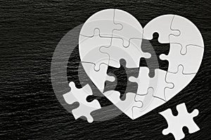 Heart-shaped jigsaw puzzle on color background. Puzzle heart on wooden background. A missing piece of the heart puzzle. Heart