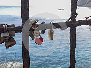 Heart-shaped keylocks on the metal bridge across the sea view close-up. Love, relationship, honeymoon, St. Valentine`s Day concept
