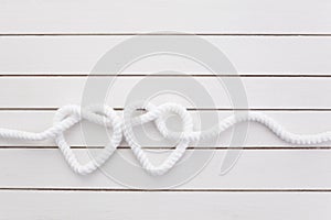 Heart shaped knot on white wooden background