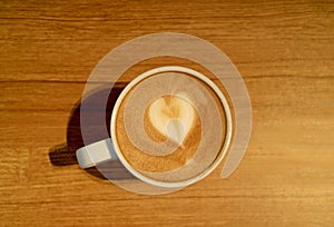 Heart Shaped Latte Art of Hot Cappuccino Coffee with Latte Art in a White Cup Served on Wooden Table