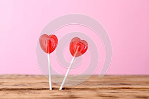Heart shaped lollipops on color background, space for text