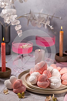 Heart-shaped meringues, pink cocktails and candles creating romantic atmosphere photo