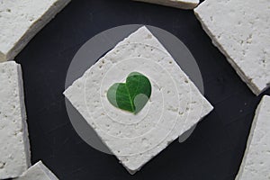 Heart shaped moringa or malunggay leaf on an uncooked tofu or soy bean curd
