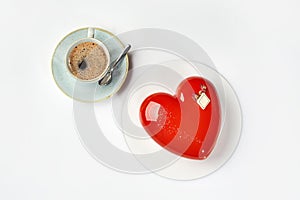 Heart shaped mousse cake in red icing with cup of espresso