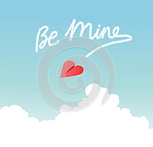 Heart shaped paper airplane flying over fluffy clouds and skywriting Be Mine.