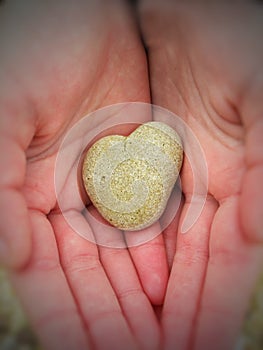 Heart-shaped pebble in a child's hands