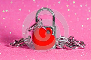 Heart shaped pendant chained to a padlock on pink